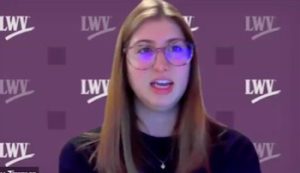 Woman with glasses speaking against a purple "LWV"-patterned background.