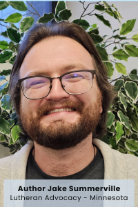 Person smiling against a background of green leaves.