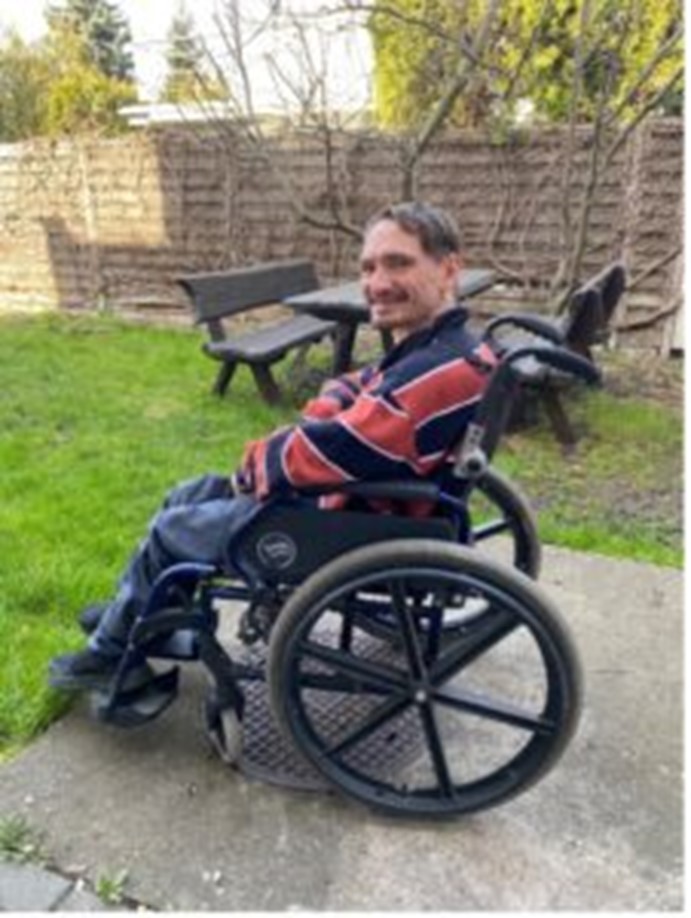 A photo of Igor Gusez in his wheelchair in a garden.