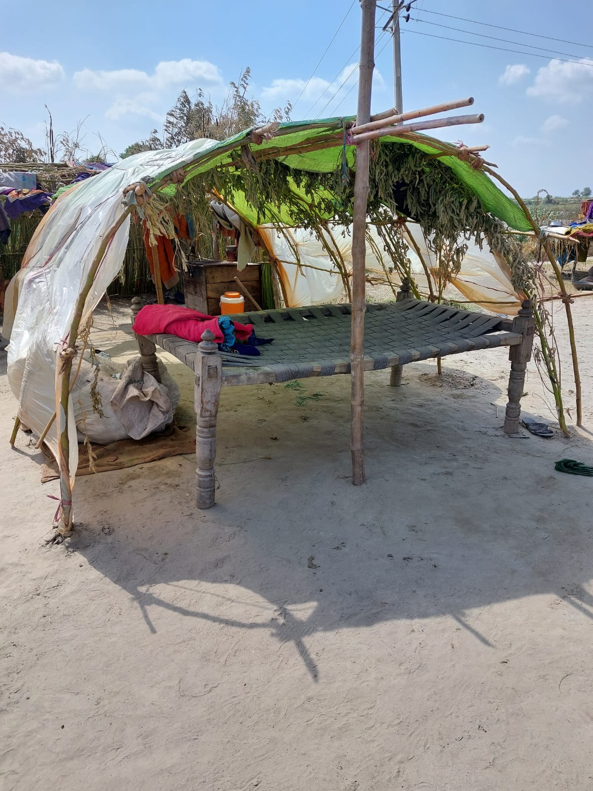 A makeshift shelter made of wooden poles and tarps.