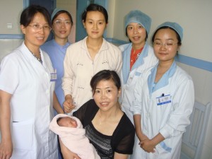 Baby Chen En, held by Pr. Liao, her mother standing behind, and surrounded by hospital staff
