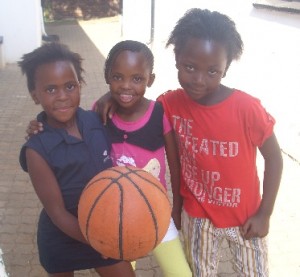 Three children in the after-school program take a break from playing ball.