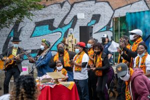 A Christian congregation gathers outside a mural for worship.