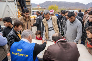 Five-year-old Vian Shara stands in the crowd at a distribution of food in Northern Iraq with her father, Saeed Shara.