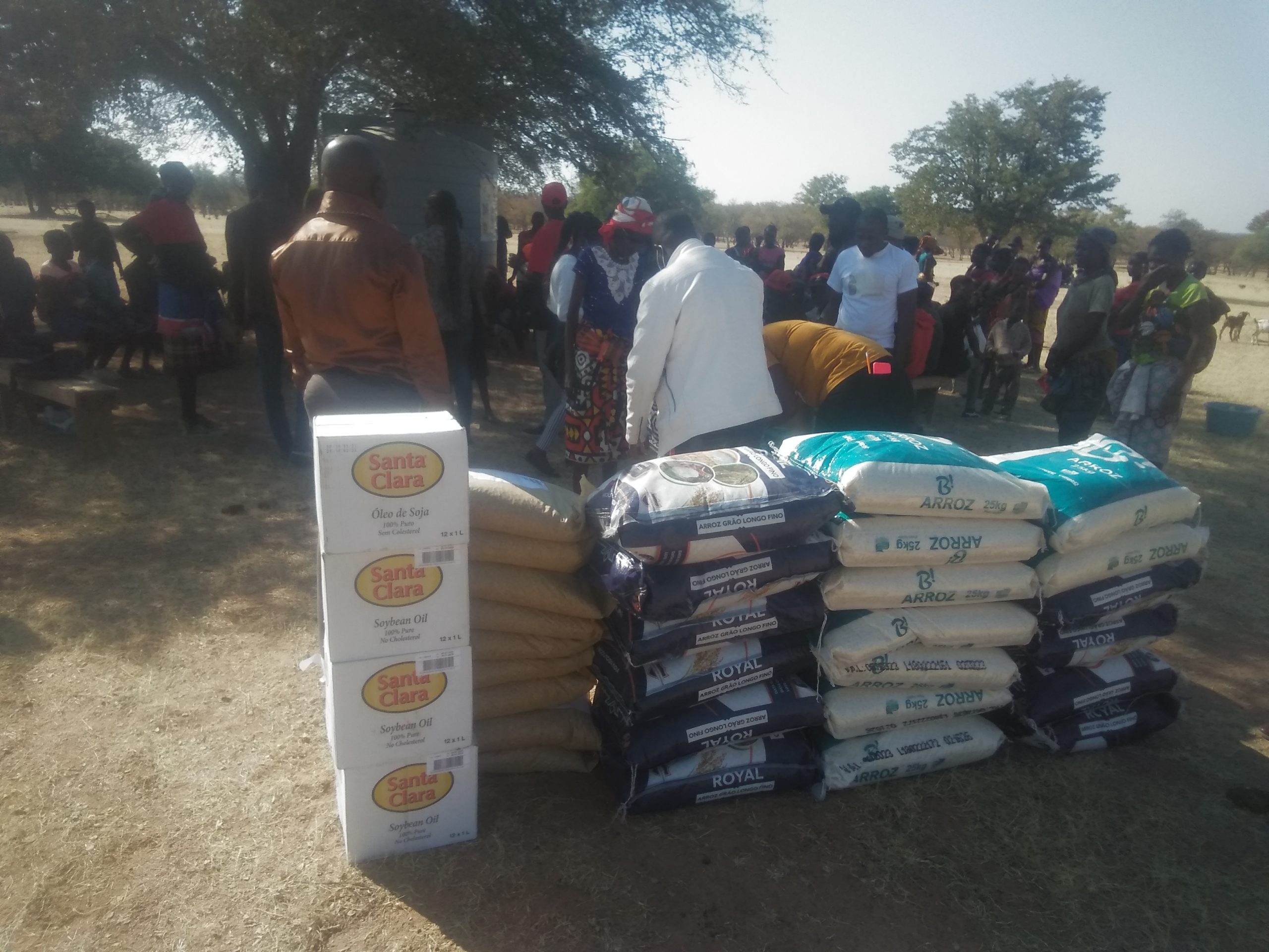 Stacks of food packages in the foreground and a group of people socializing behind them.