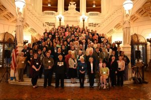 Group photo of individuals on an ornate staircase inside a grand building. 