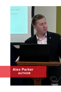 A man speaking at a podium with a presentation screen behind him. Transcribed Text: Alex Parker AUTHOR